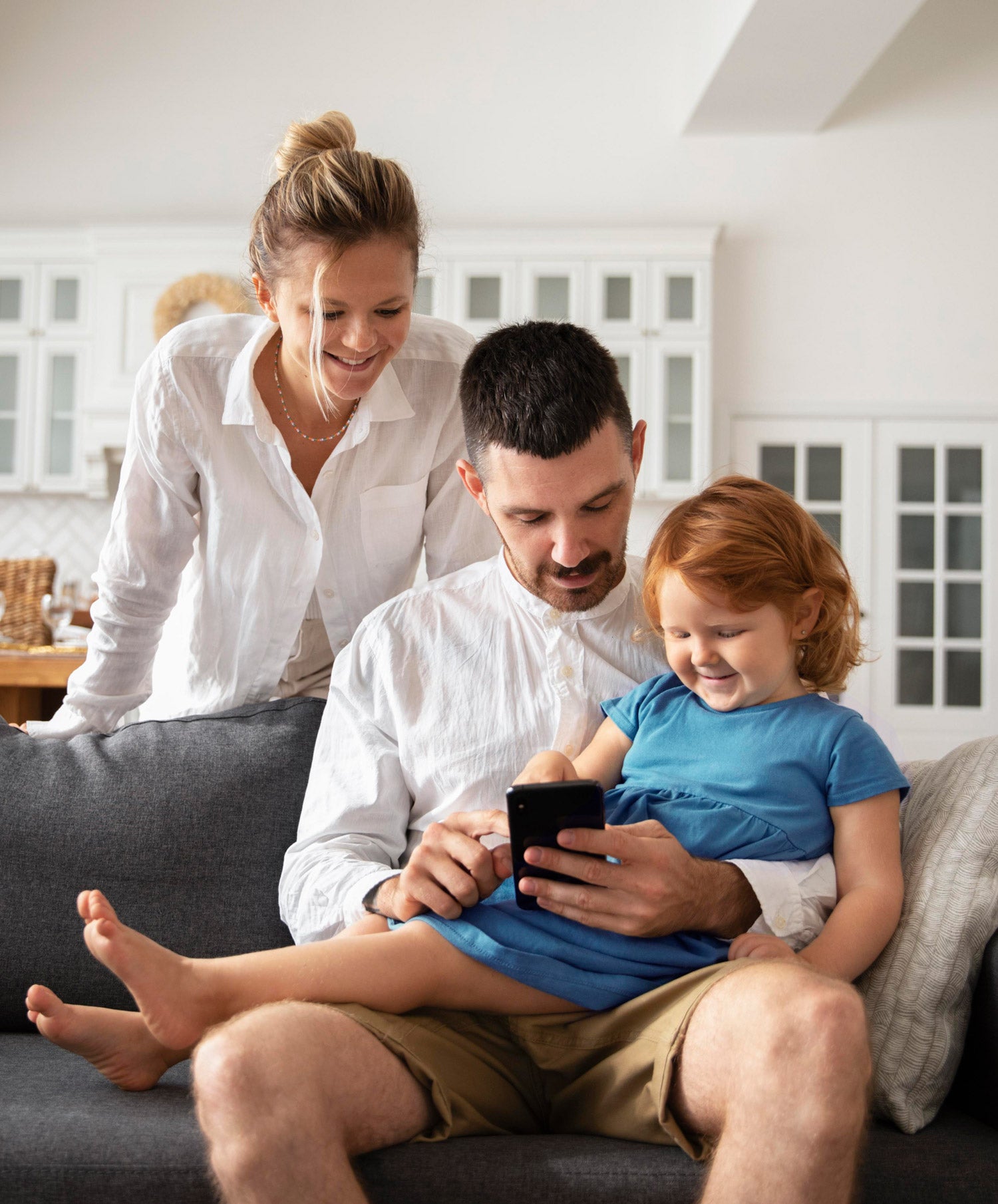 Happy-homeowners-using-mobile-device-in-living-room-to-arm-security-system-at-home