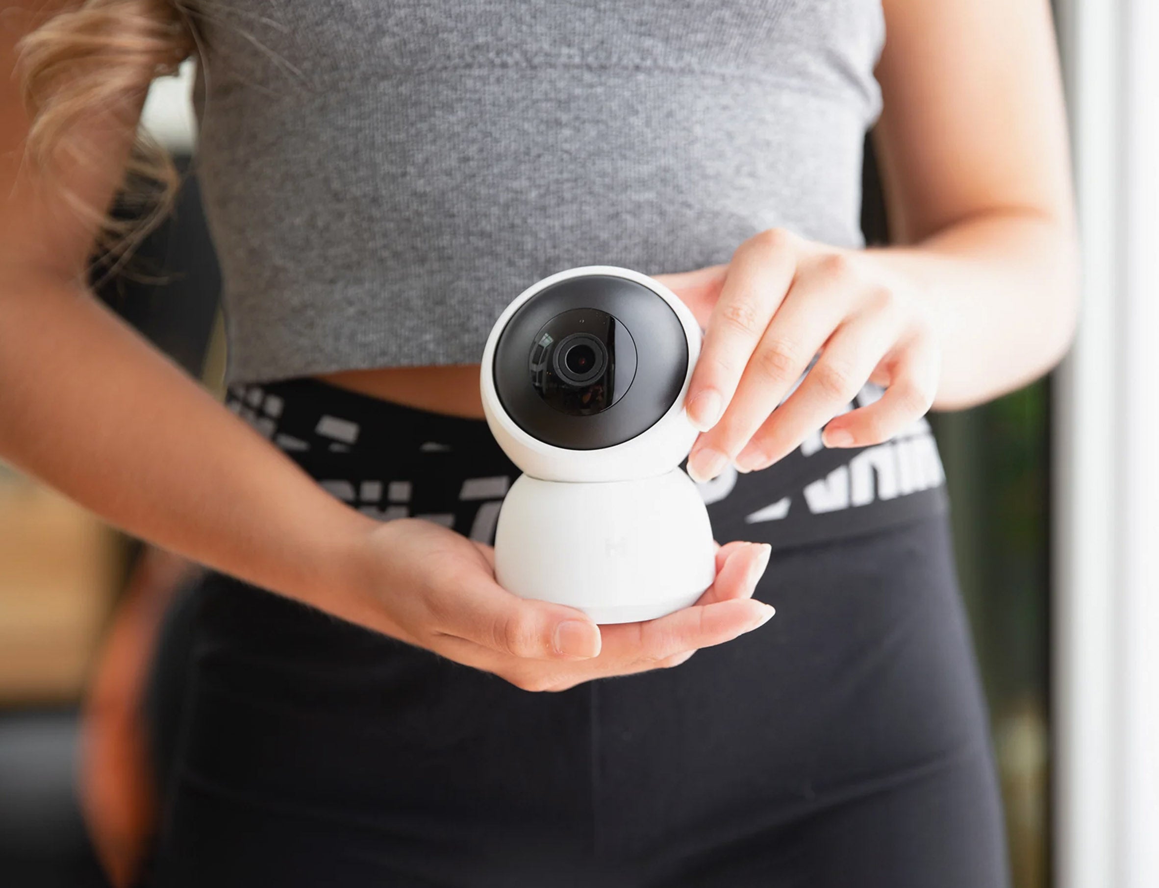 woman-holding-small-white-security-camera-a1-with-hands-in-front-of-her