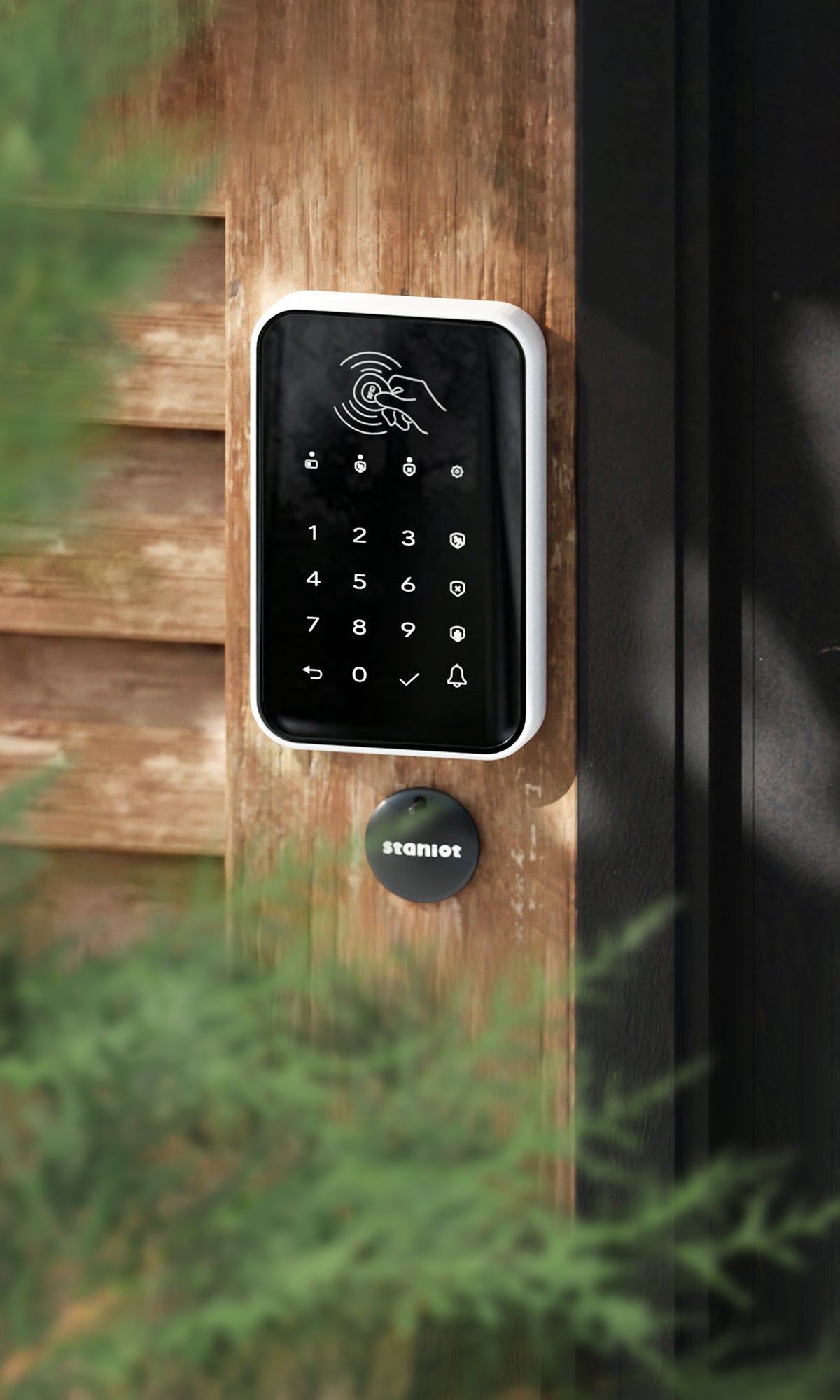 Staniot K010, RFID Wireless Alarm Touch Pad near home door entry with green vegetation on the far left